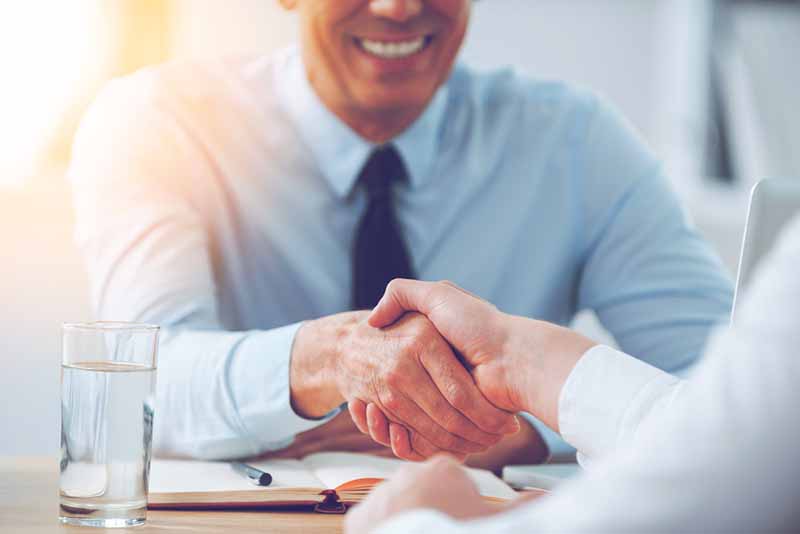 Close-up of two guys shaking hands while sitting at the working place